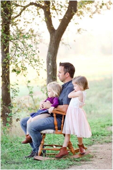 Daddy's little girls sitting on his lap on the rocking chair.